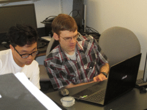 Brooks Thomas looks at a computer screen with a student.