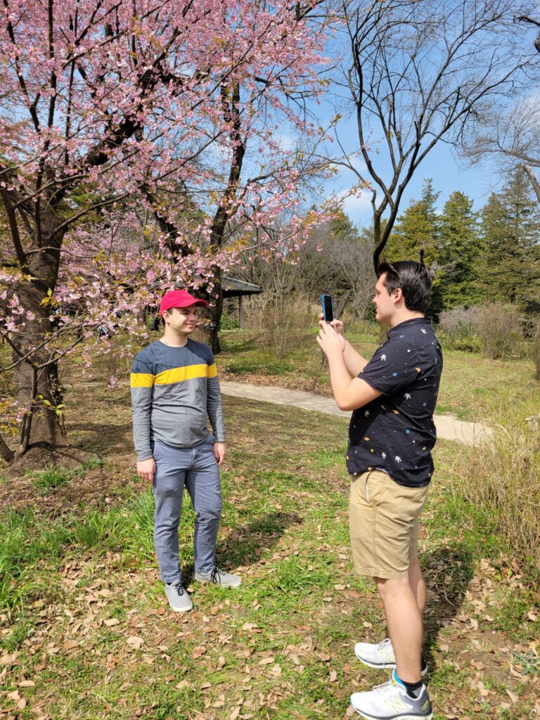 A photo of Josh taking a photo of Ben by a cherry blossom tree