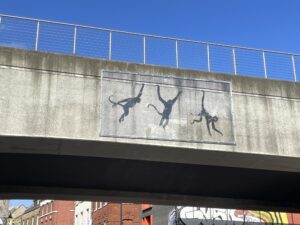 concrete overpass with images of swinging monkeys painted by Banksy