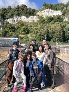 Group of students, children, and professor on pier in front of chalk cliffs