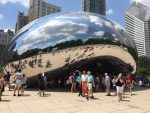 Tourists mill around a huge mirrored bean-like sculpture.